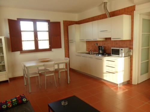a kitchen with white cabinets and a table and chairs at Borgo Etrusco in Scarlino