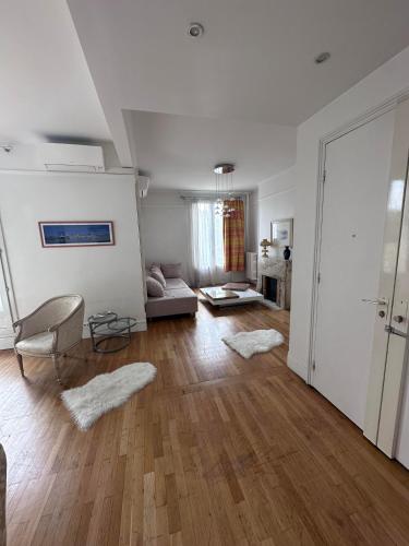 Il comprend un salon doté de murs blancs et de parquet. dans l'établissement Luxueux appartement à la Porte d'Auteuil - 16ème Arrondissement, à Paris