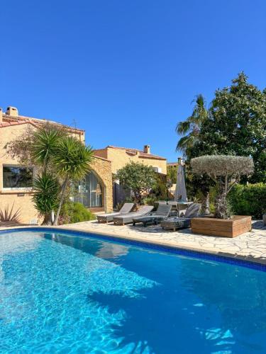 une grande piscine bleue avec chaises et parasols dans l'établissement Villa ESPERANCE- appartement entier T2, à La Ciotat