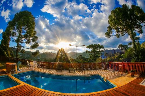 a swimming pool with the sun in the background at Mansão Austríaca Guesthouse in Campos do Jordão