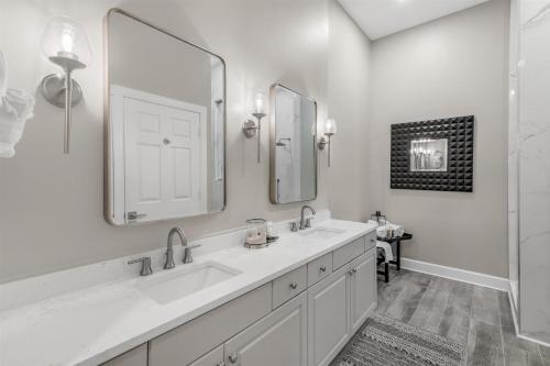 a white bathroom with two sinks and a mirror at Seacrest - The Wellington in Panama City Beach