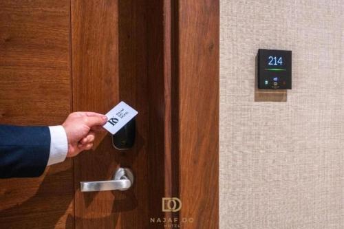 a person holding a door handle with a card at Najaf Do Hotel in An Najaf