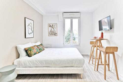 une chambre blanche avec un lit et une table dans l'établissement Petit studio moderne à Asnières, à Asnières-sur-Seine