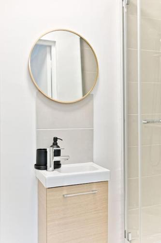 une salle de bain avec un lavabo et un miroir au mur dans l'établissement Petit studio moderne à Asnières, à Asnières-sur-Seine