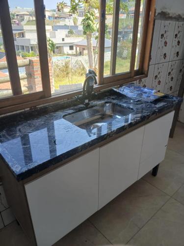 a kitchen counter with a sink and a window at Chacara em Condomínio in Mairinque