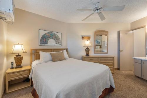 a bedroom with a white bed and two nightstands and two lamps at Maui Sunset A413 in Kihei