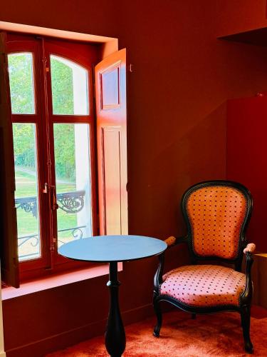 a table and a chair in front of a window at Les Hayes en Sologne in Fontaines-en-Sologne