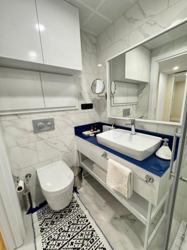 a white bathroom with a sink and a toilet at EVIS LTD apartments Batumi 2 in Angisa