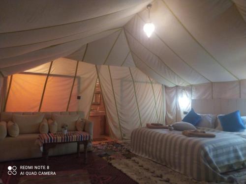 a bedroom with a tent with a bed and a couch at Berber Camp Merzouga in Merzouga