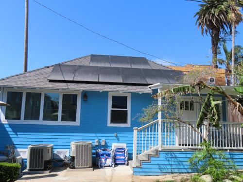 a blue house with a solar roof on it at Hill Street Cottage in Los Angeles