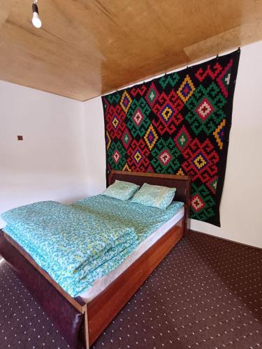 a bed in a room with a blanket on the wall at MusoBarakaNur Guest House in Yukary-Ukhum