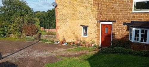 a brick house with a red door and a yard at Hill House in Banbury