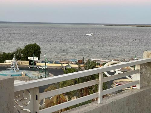 a white fence with a view of the water and a boat at Divers Home Safaga in Safaga 