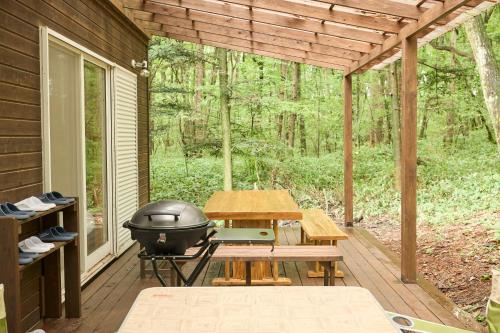 a screened in porch with a grill and picnic table at モリテラス凛 -北軽井沢- in Naganohara