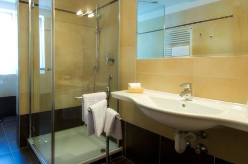a bathroom with a sink and a glass shower at Hotel Weingarten in Caldaro