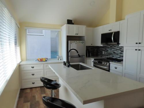 a kitchen with white cabinets and a sink at Hill Street Cottage in Los Angeles