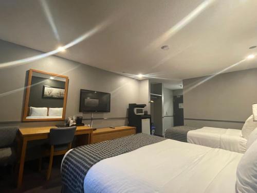 a hotel room with two beds and a desk and a mirror at Travelodge by Wyndham Brandon in Brandon