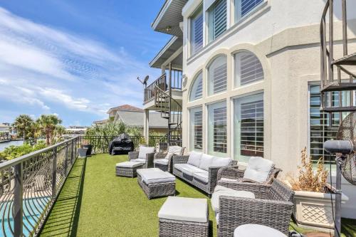 Un patio con sillas y mesas en un balcón. en Waterfront Dream House Pool Golf Cart & Dock, en Destin