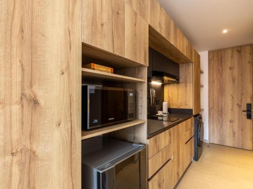 a kitchen with wooden cabinets and a microwave at Muttuo by Wynwood House in Bogotá