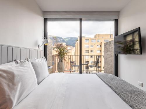 a bedroom with a white bed and a balcony at Muttuo by Wynwood House in Bogotá