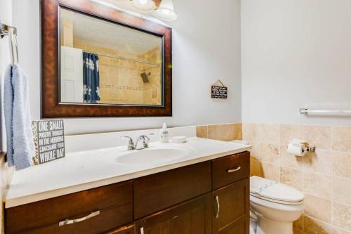 a bathroom with a sink and a toilet and a mirror at Grand Retreat Sleeps 12 Spacious Deck and WiFi in Fairington