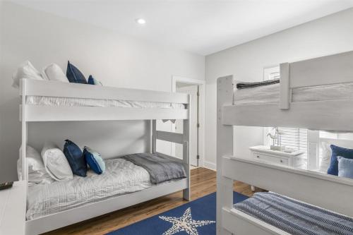 sypialnia z dwoma łóżkami piętrowymi z niebieskimi poduszkami w obiekcie Seacrest West - 8 Wisteria w mieście Seacrest