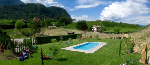 a garden with a swimming pool in the middle of a field at Hotel Weingarten in Caldaro