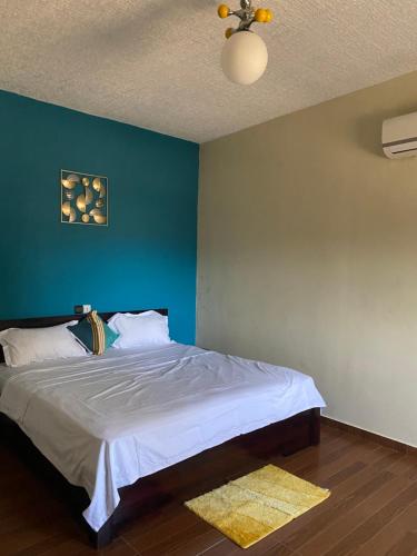 a bedroom with a bed with a blue wall at Appart Cozy Djidjolé in Aboni Kopé