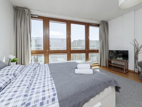 a bedroom with a large bed and a large window at Luxury apartment Piękna in Warsaw