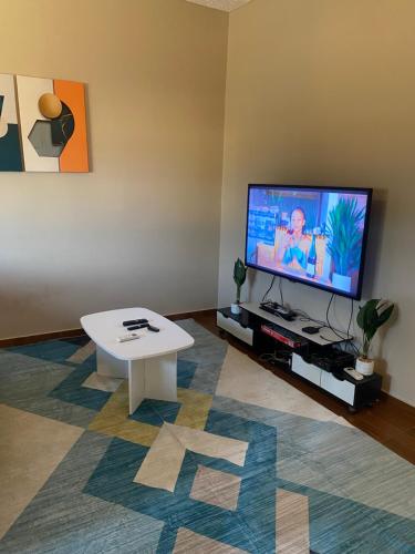 a living room with a tv and a white coffee table at Appart Cozy Djidjolé in Aboni Kopé