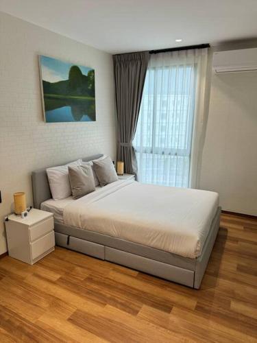 a bedroom with a large white bed with a window at Super Naiyang Title 1Bdr 600m to beach in Nai Yang Beach