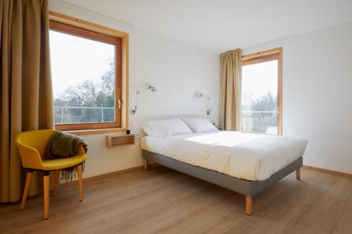a bedroom with a bed and a yellow chair at La Ferme Des Ailleurs in Arleux-du-Nord