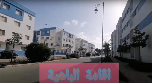 a pink sign on the side of a street with buildings at Marhaban U2 in Martil