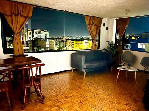 a living room with a blue couch and a large window at Departamento vista espectacular Norte-centro Quito in Quito