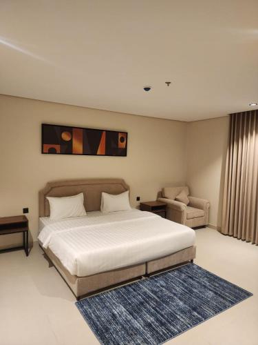 a bedroom with a large white bed and a chair at المهيدب للشقق الفندقية in Rabigh