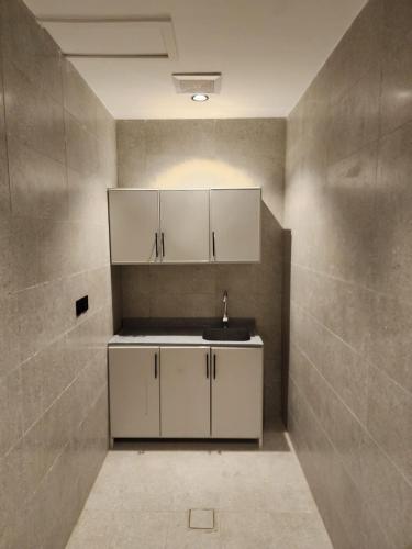 a kitchen with white cabinets and a sink at المهيدب للشقق الفندقية in Rabigh