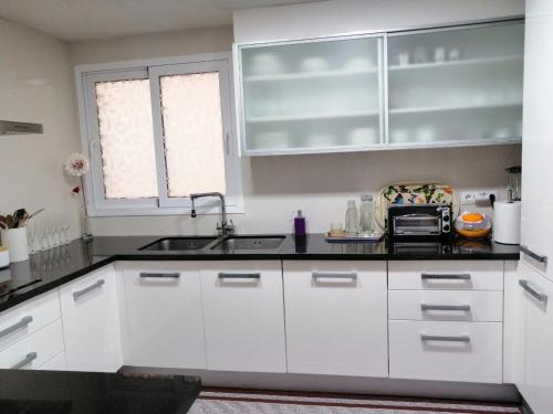 a kitchen with white cabinets and a sink at Habitaciones doble in Almussafes