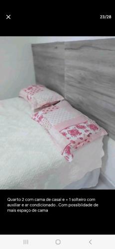 a white bed with a pink blanket and two pillows at Casa cataratas 3 in Foz do Iguaçu