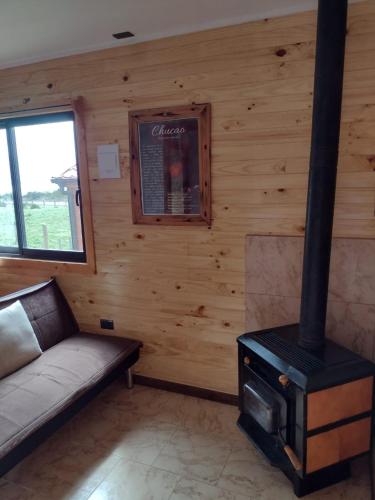 a living room with a fireplace and a couch and a stove at Cabañas Piedra de Condores in Bahía Murta