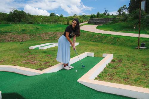 a woman playing golf on a putting green at Cassino All Inclusive Resort Poços de Caldas By Nacional Inn in Poços de Caldas
