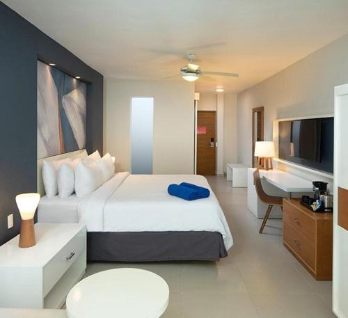 ein Hotelzimmer mit großem Bett und Schreibtisch in der Unterkunft Emotions by Hodelpa - Juan Dolio in Juan Dolio