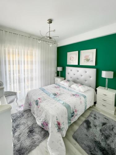 a bedroom with a bed and a green wall at Guesthouse Santos & Belos in Nazaré