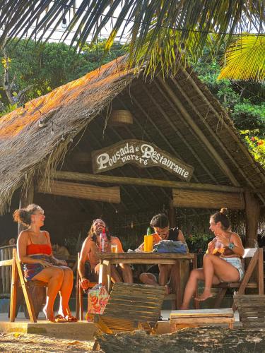 eine Gruppe von Menschen sitzt an einem Tisch am Strand in der Unterkunft Pousada Moreré in Ilha de Boipeba