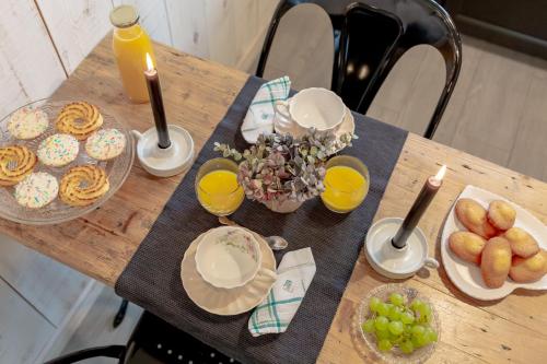 a wooden table topped with plates of food and orange juice at Charmant gîte cosy et romantique à Sanguinet in Sanguinet