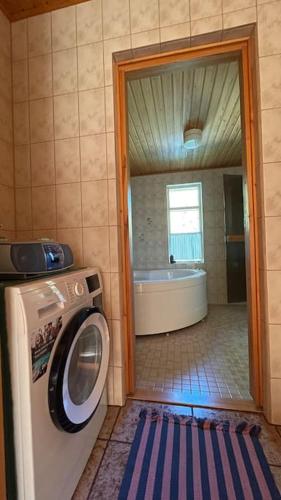 a bathroom with a washing machine and a tub at Keltainen talo - tilava huvila lähellä Saloa in Vartsala