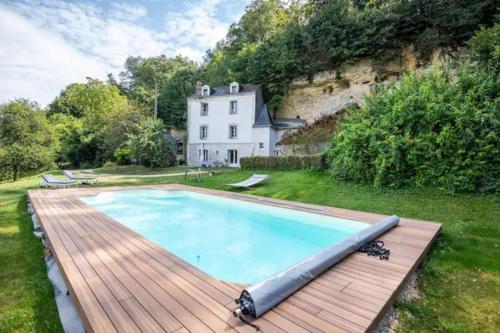 une piscine avec une terrasse en bois devant une maison dans l'établissement Les Roches, charmante troglodyte à Amboise, à Amboise