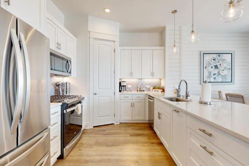 a white kitchen with white cabinets and a refrigerator at Sabal by the Sea in Port Aransas