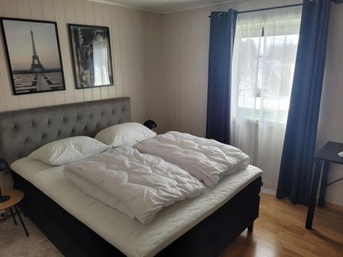 a bedroom with a bed with white sheets and a window at Romslig leilighet midt i Lofoten in Leknes