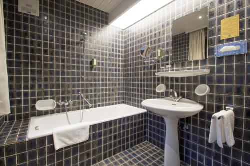 Baño de azulejos azules con lavabo y espejo en Hotel Garni Römerhof, en Innsbruck