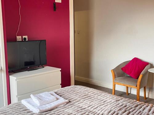 a bedroom with a bed and a tv and a chair at The Beechwood in Leeds